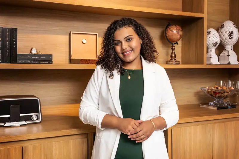 Advogada de blazer branco em escritório com estante de madeira